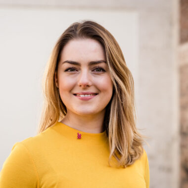 Rhiannon Ewing-James stands in front of the Spode Factory building wearing a yellow top.