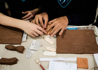 Children stamp the surface of red clay and make marks with tools.