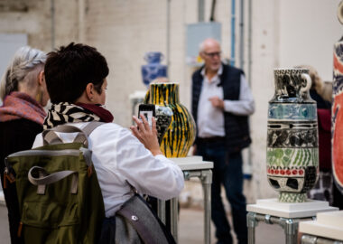 Woman takes photo of ceramics vases at British Ceramics Biennial