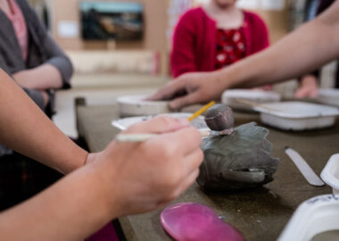 A festival visitor paints slip (liquid clay) onto a teacup.