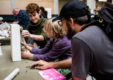 Artist Sarah Fraser demonstrates a press moulding technique using raw clay and a white ceramic mould to a visitor. The photo was taken during BCB's 2019 festival.