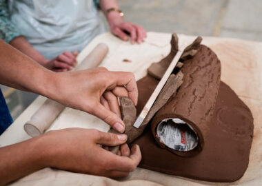 Two people work together on a terracotta sculpture.