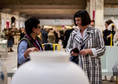 A large ceramic vessel by Adam Buick sits in the foreground in front of two women visiting British Ceramics Biennial 2019.