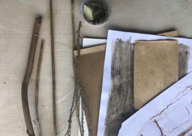 Sticks, handmade ink and assorted pieces of paper are laid out on a table as an indication of what people will do in the workshop.