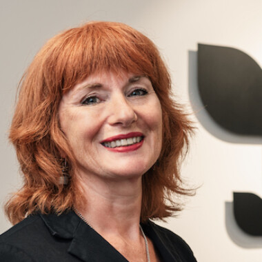 Sara is stood in front of a Staffordshire Chambers of Commerce logo wearing a black suit.