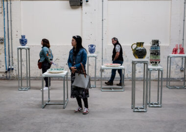 Festival visitors stand among ceramics displayed on plinths at varying heights.