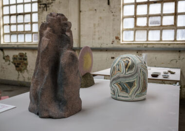 Three ceramic sculptures are displayed on a table, backlit by light in Spode Factory Hall.