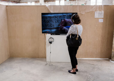 A festival visitor watches a film on a tv screen with a pair of headphones on.