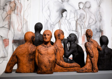 Ceramic torsos by artist Christie Brown are set against a backdrop of pencil drawings of human figures.