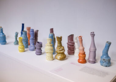 Many small and colourful vases are grouped. They have slumped forms and crackled and bubbly surfaces.