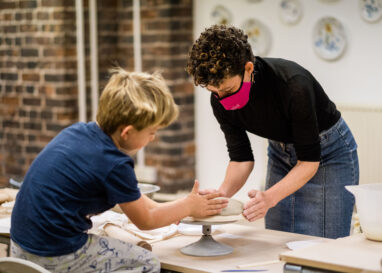 A child is making a plate with the help of a BCB Associate Artist.