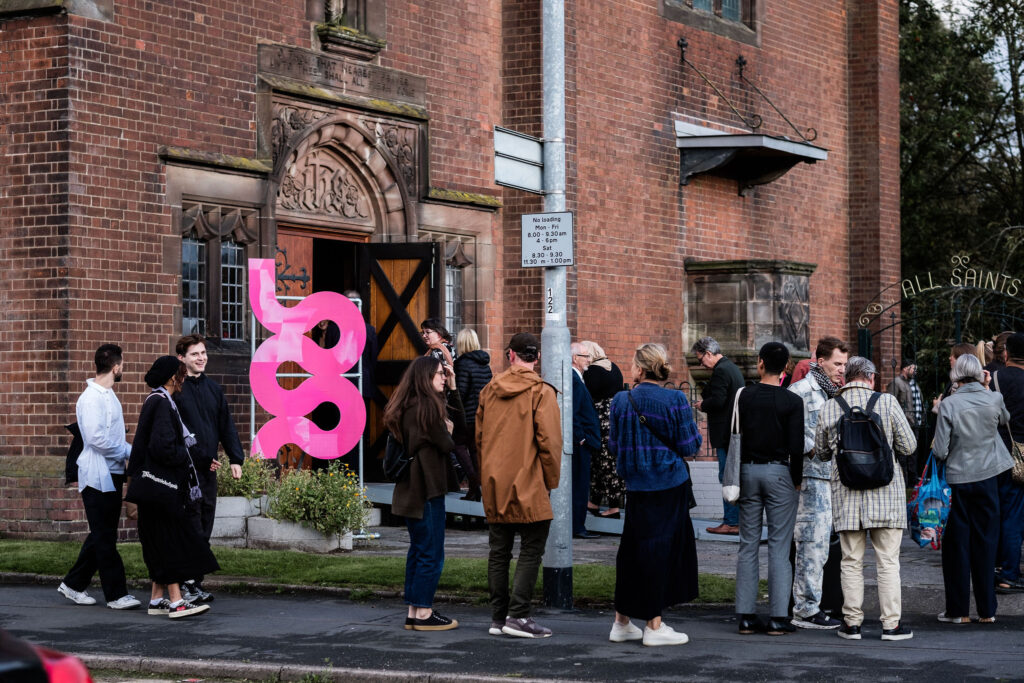 A line of people waiting to get into the opening night of the 2023 British Ceramics Biennial at All Saints Church in Stoke-on-Trent.