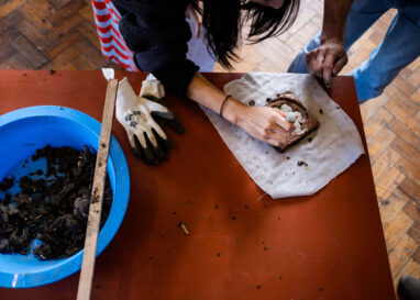 A person is squeezing clay slip onto a tile in the Tactile Project Space.