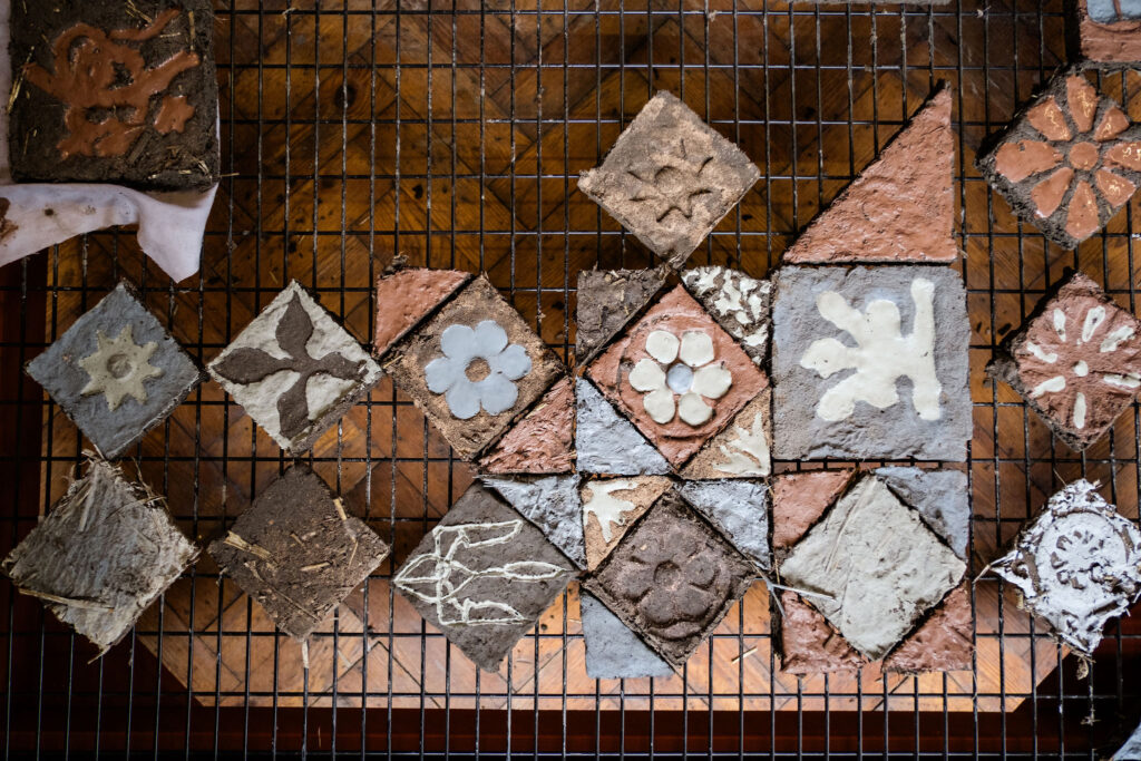 A grid of clay tiles laying out to dry on a metal rack.