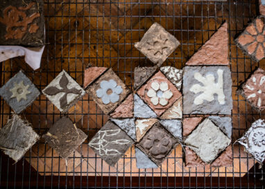 A grid of clay tiles laying out to dry on a metal rack.