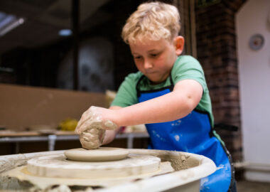 A child is throwing a pot on a potter's wheel.