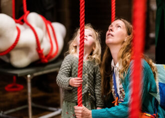 A parent and child hold a red rope as part of Mella Shaw's work at the 2023 British Ceramics Biennial.