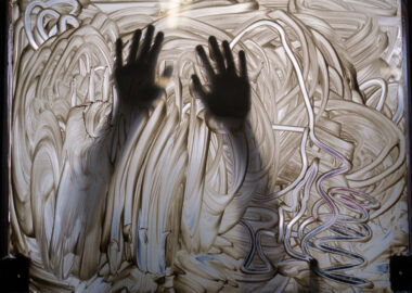 A silhouetted pair of arms against a window covered in clay slip.