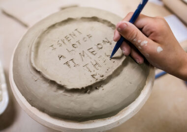 In-progress plate, upside down with someone carving the words "I spent a lot of time on this".